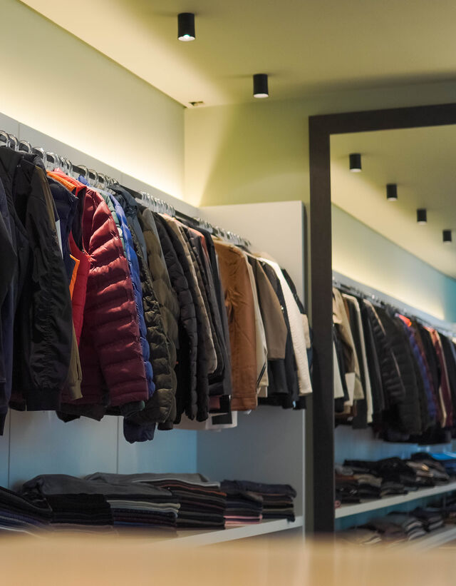 Araras do showroom com jaquetas e malhas de várias origens
